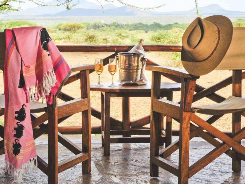 Deux chaises en bois avec une couverture et un chapeau sur une terrasse avec vue sur le paysage.