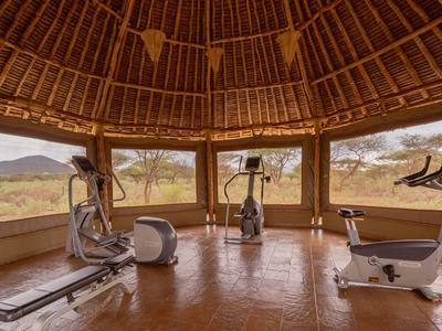 Fitnessraum mit großen Fenstern und Holzdecke mit Blick auf die Landschaft.