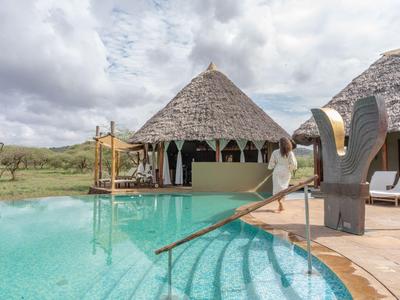 Runder Pool mit Stroh gedecktem Pavillon und offenem Bereich in einer Lodge im Freien.