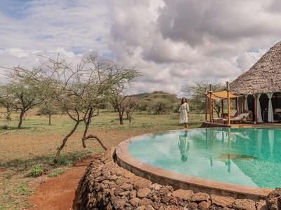 Runder Pool mit Blick auf afrikanische Landschaft und Baum in der Nähe eines Hotelresorts.