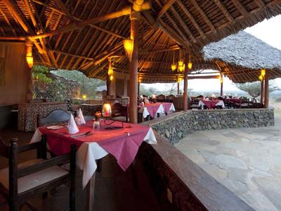 Offenes Restaurant mit Holzdach und rot gedeckten Tischen in einer naturnahen Umgebung