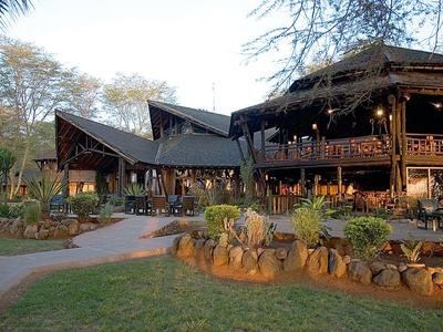 Large rustic wooden building in a wooded hotel area at sunset.