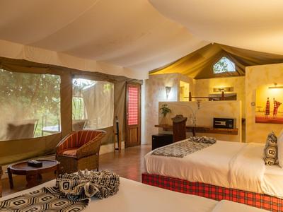 Cozy hotel room with two beds, seating area, and large window overlooking greenery.