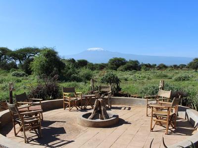 Outdoor fire pit area with chairs overlooking green landscape and mountain in the background.