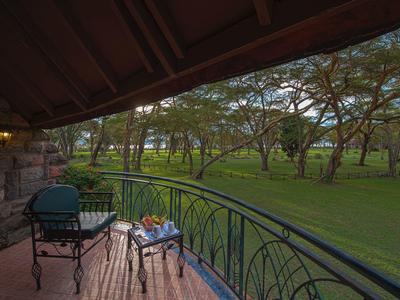 Balcony with chair and table overlooking a green, wooded landscape at dusk.