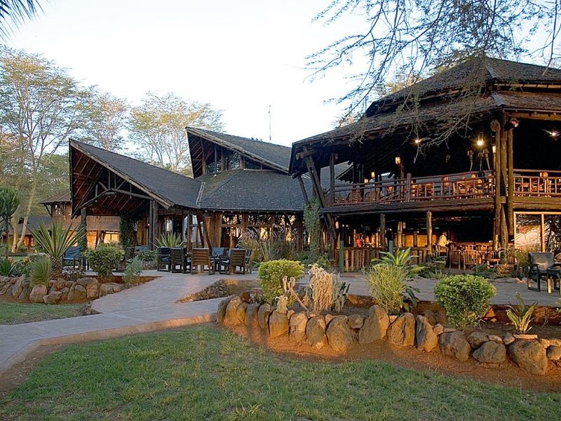 Large rustic wooden building in a wooded hotel area at sunset.