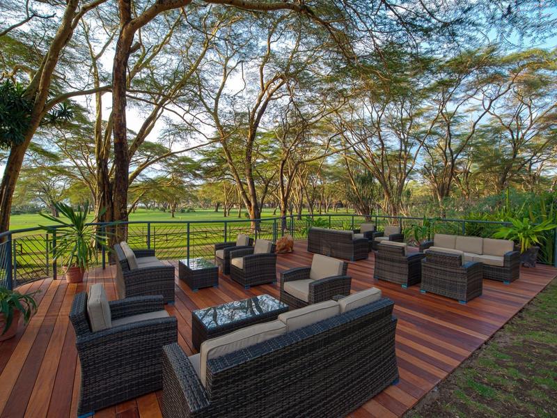Cozy wicker seating area on wooden deck overlooking lush green parkland.