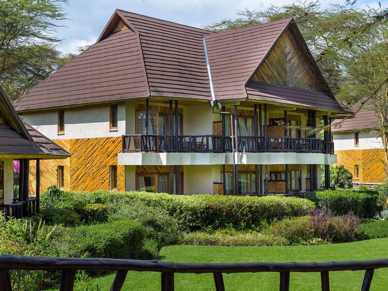 Modern two-story vacation house with balcony and green garden in a peaceful setting.