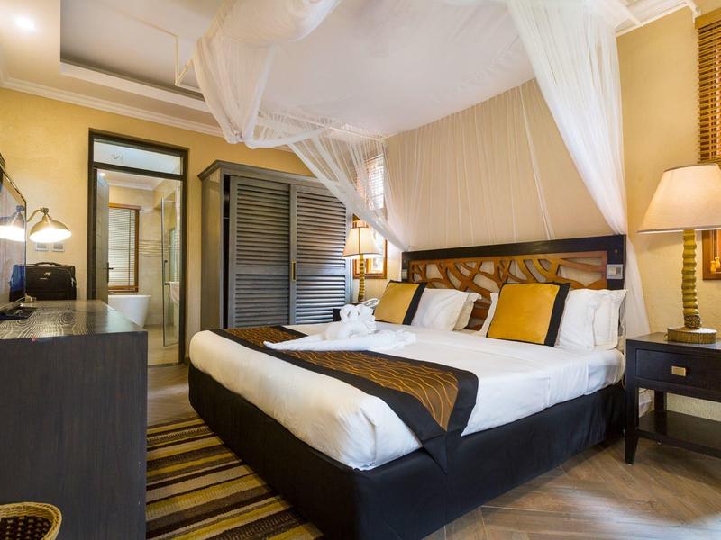 Cozy hotel room with large bed, mosquito net, and adjoining bathroom.