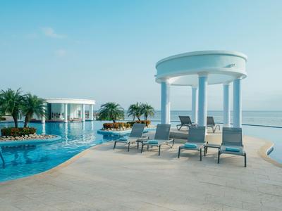 Modernes Resort mit Pool, weißen Pavillons und Liegestühlen am Meer