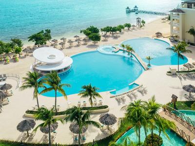 Großer Hotelpool mit Palmen und Blick auf den Strand und das Meer.