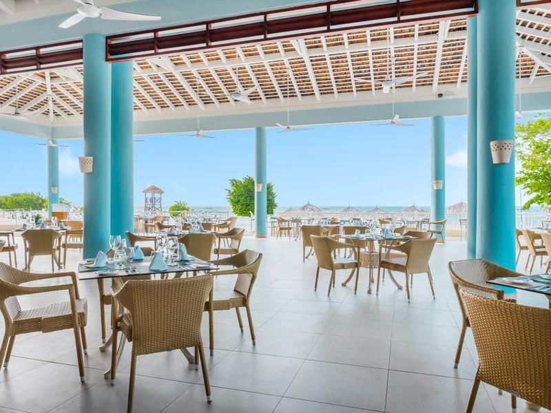 Open restaurant area with tables and chairs offers sea view and clear weather.