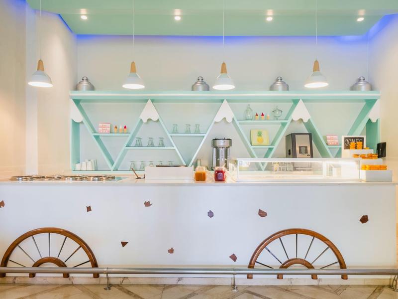 Modern hotel bar with white counter and blue LED lighting on the ceiling.