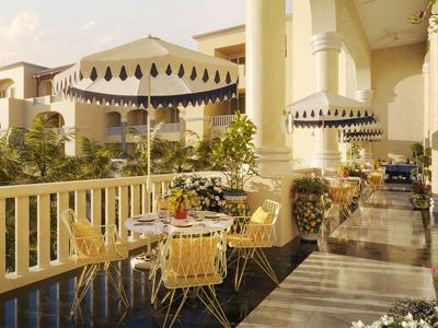Hotelterrasse mit gelben Tischen und Stühlen neben einem Wasserbecken und Pflanzen.