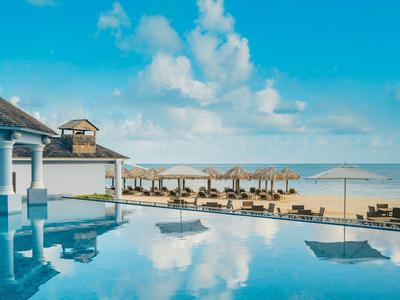 Moderner Pool mit Blick auf den Sandstrand und blauen Himmel am Hotel.