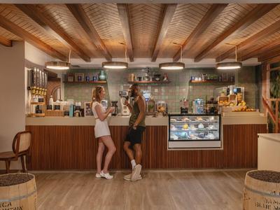 Zwei Frauen stehen in einem gemütlichen Café mit Holzbalkendecke und großer Theke.