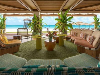 Offener Loungebereich mit bequemen Sitzmöbeln und Blick auf den Strand und das Meer.