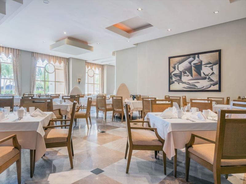 Světla a elegantní restaurace s prostřenými stoly a velkými okny.