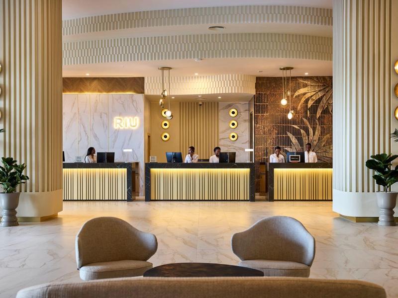 Moderne Hotellobby mit Sitzgelegenheiten, großen Säulen und einem hell beleuchteten Empfangstresen.