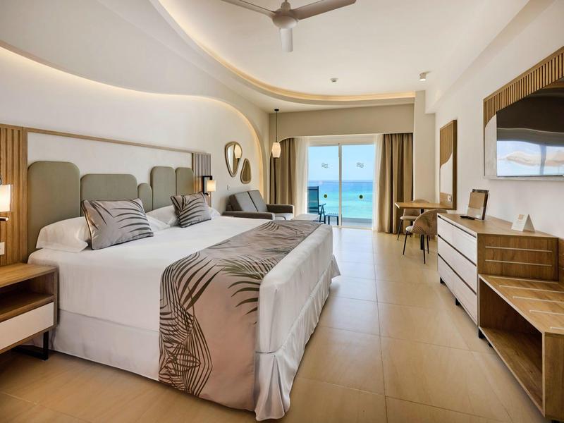 Modernes Hotelzimmer mit großem Bett, Holzvertäfelung und Balkon mit Meerblick.