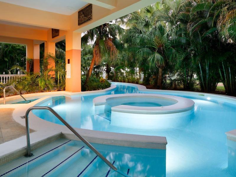 Un jacuzzi con escalera en una terraza junto a vegetación tropical verde.