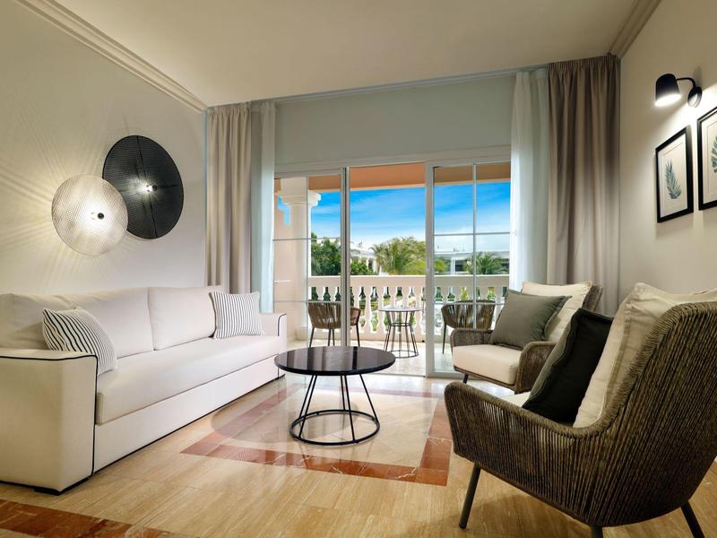 Modern eingerichtetes Wohnzimmer mit weißem Sofa, grauen Sesseln und großem Fenster zur Terrasse.