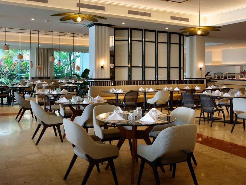 Ein elegantes Hotelrestaurant mit modernen Stühlen und Tischgedecken in warmem Licht.