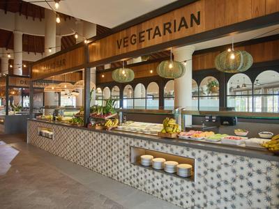Großer vegetarischer Buffetbereich mit warmem Holz, Glaslampen und Mosaikfliesen.