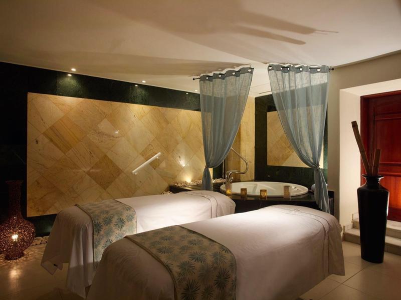 Elegantní ošetřovací místnost se dvěma masážními lůžky, závěsy a atmosférickým osvětlením.