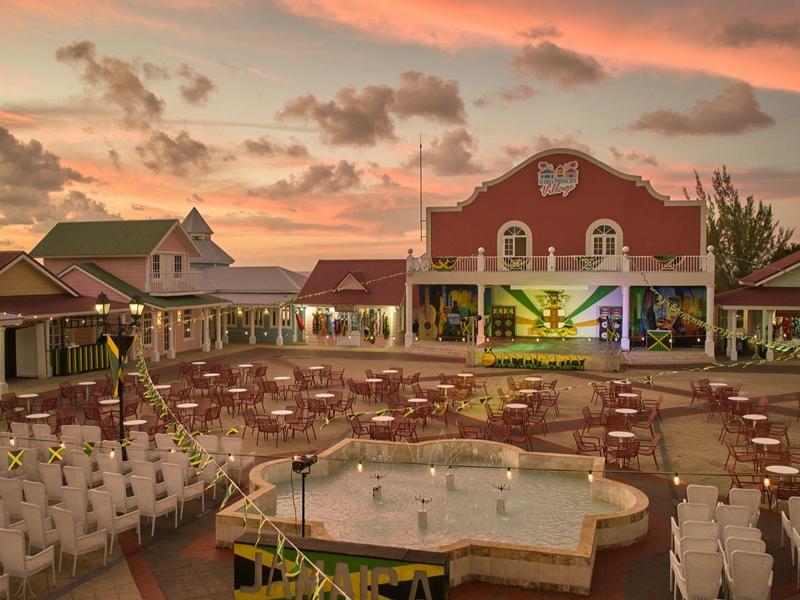 Velká venkovní restaurace s mnoha židlemi a pódiem za západu slunce.