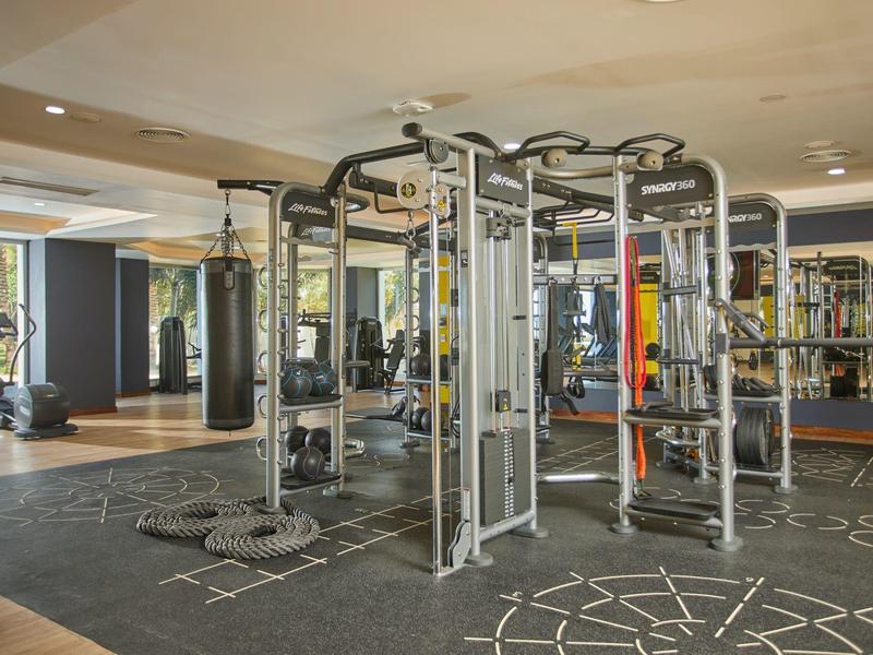 Moderne fitnessruimte met multifunctionele trainingsapparatuur en spiegelwanden.