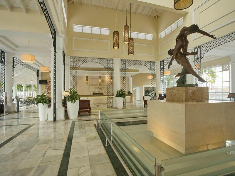 Lichte ruime hotelhal met marmeren vloer en een moderne sculptuur in het midden.