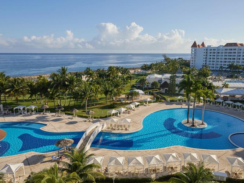 Hotelzwembad met glijbaan, parasols en tropische tuin aan zee