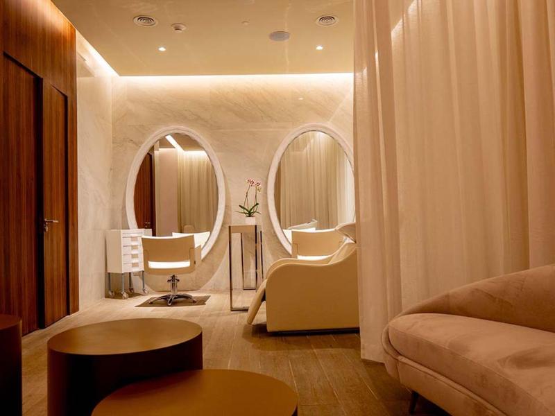 Eleganter Raum mit warmem Licht, ovalen Spiegeln, hellen Wänden und bequemen Polstermöbeln.