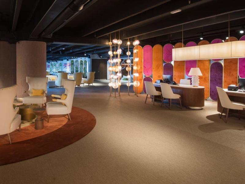 Moderne Lounge mit bunten Wänden, runden Sesseln und gemütlicher Beleuchtung in warmen Tönen.