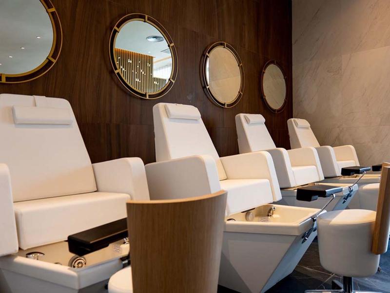 Moderne Pediküre-Stühle in einem stilvollen Salon mit runden Spiegeln an der Wand.