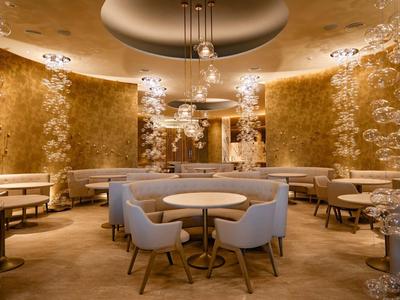 Elegant round table with light blue chairs in a warmly lit room with golden walls.