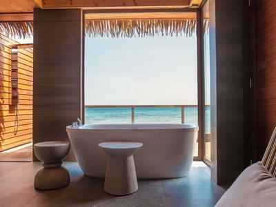 Freestanding bathtub with a view of the sea through a large opening in the wooden interior.