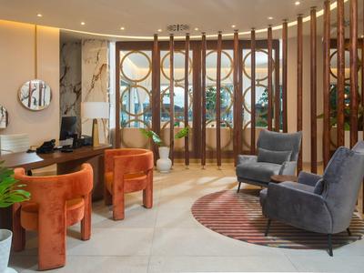 Modern hotel lounge with sofas, armchairs, and decorative wooden elements.