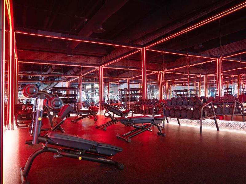 Modern gym with red neon lights and extensive workout equipment.