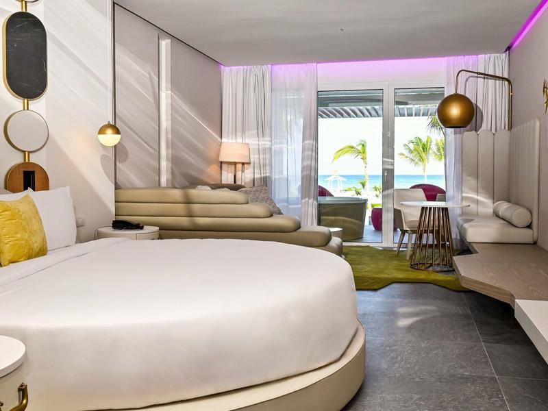 Modern hotel room with round bed, seating area, and balcony with a view.