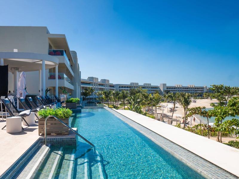 Modern pool overlooking palm trees and buildings on a sunny day.