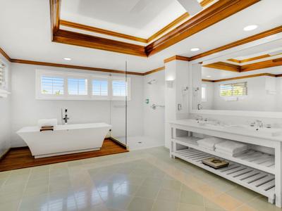 Helles Badezimmer mit freistehender Badewanne, großer Spiegelwand und Holzdecke mit Einbaustrahlern.