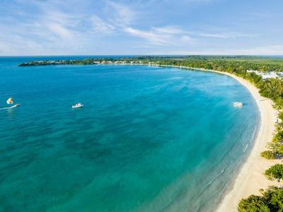 Szeroka zatoka z turkusową wodą i długą piaszczystą plażą wzdłuż zalesionego wybrzeża.
