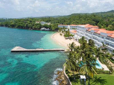 Hotel an einem tropischen Strand mit weißem Sand, blauem Wasser und Palmen.