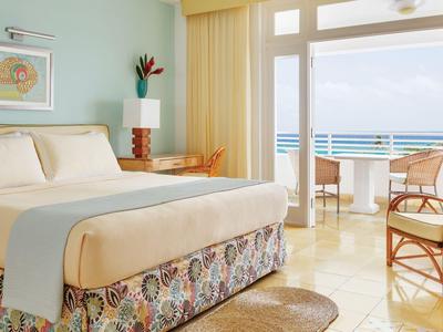 Helles Hotelzimmer mit Doppelbett, Balkon und Meerblick.