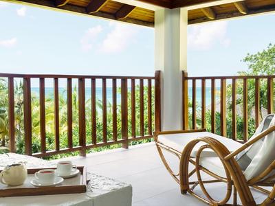 Balkon mit Stuhl und Teetablett, Blick auf grüne Landschaft unter blauem Himmel.