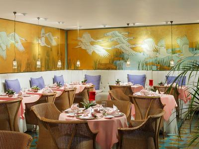 Elegantes Restaurant mit rosa gedeckten Tischen und goldener Wandgestaltung mit Engelmotive.