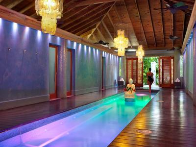 Eleganter Indoor-Pool mit Holzboden, indirekter Beleuchtung und dekorativen Kronleuchtern in einem Hotel.