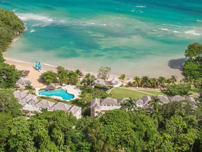 Hotelanlage mit Pool und direktem Zugang zum blauen Meer, umgeben von üppigem Grün.